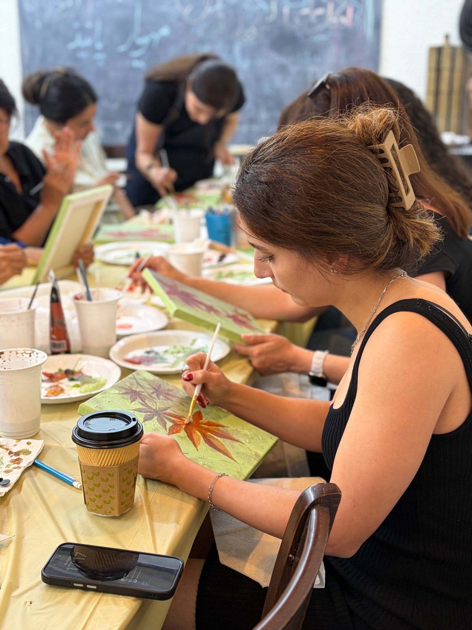 A participant painting autumn leaves at a shared table