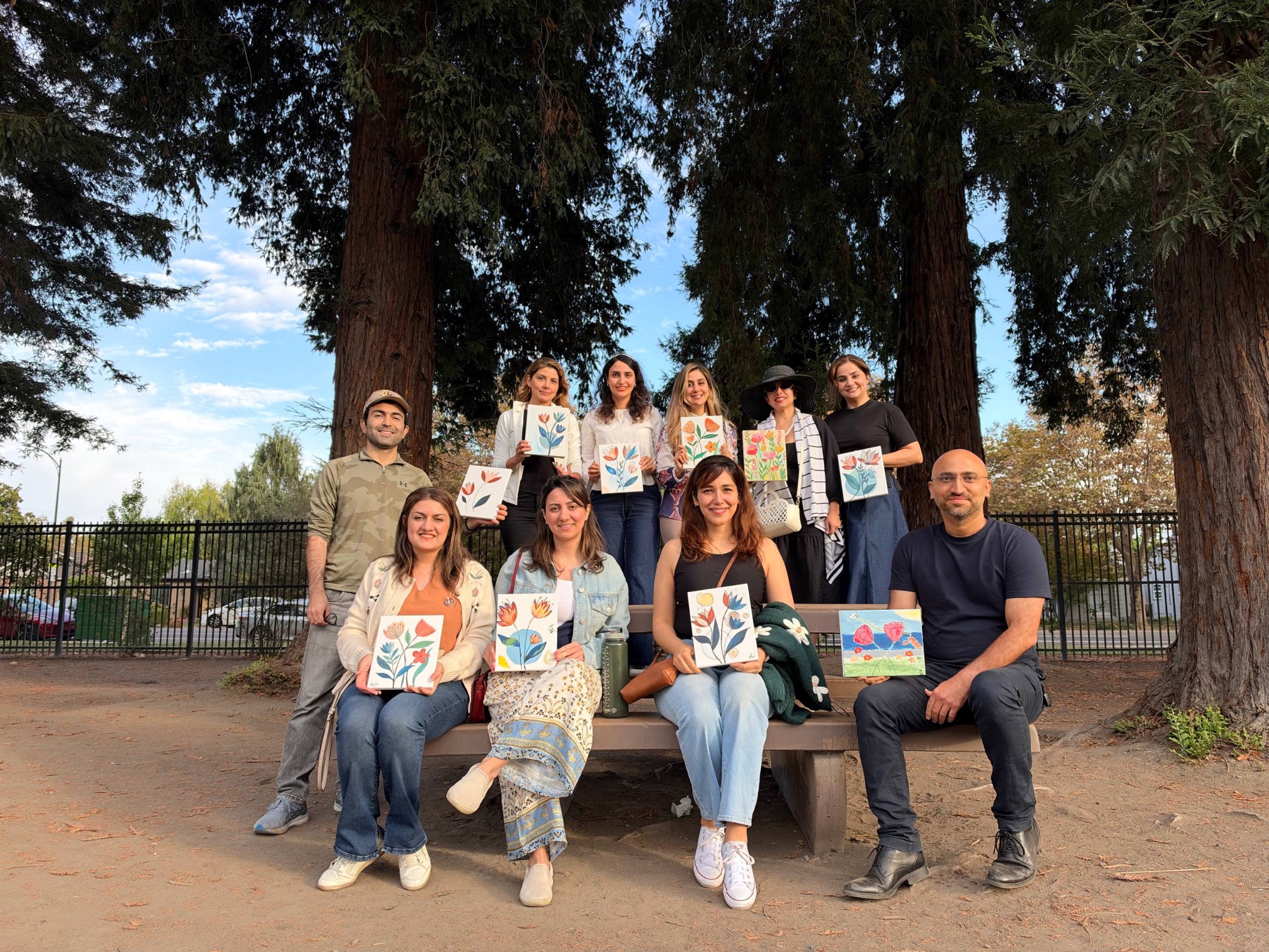 Our group holding their floral paintings beneath tall trees