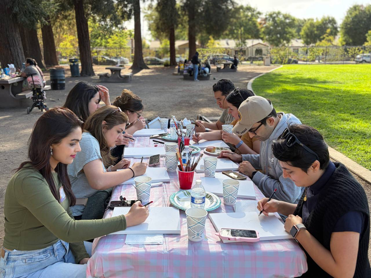 Friends painting together at an outdoor picnic table